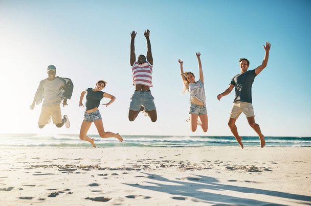 Strand, diversiteit en een groep vrienden springen in de lucht voor de zomervakantie met geluk, jeugd en opgewonden. Oceaan, multicultureel en mensen in de lucht voor schoolreünie met geheugen, energie en vrijheid. - Foto, afbeelding