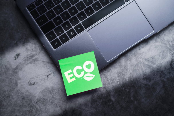 Flat lay photo of green adhesive note on laptop with ECO life text. Save the planet. Energy efficiency concept. - Фото, изображение