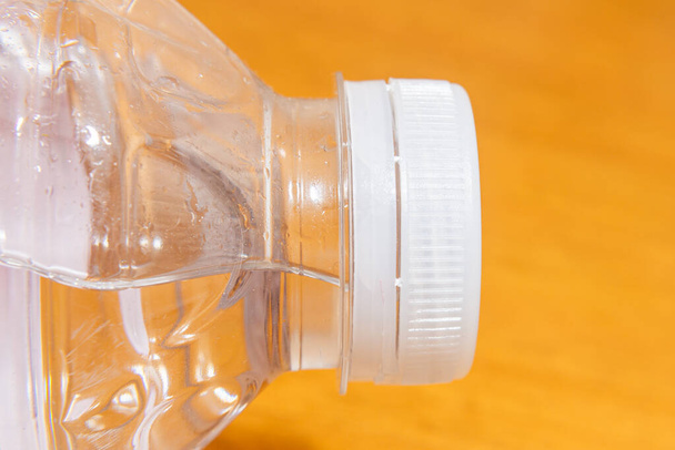 Egy műanyag palack, víz és egy műanyag dugó közelkép, makró lövés. - Fotó, kép