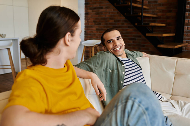 Два молодых человека в повседневной одежде разделяют момент смеха и связи в современной обстановке квартиры. - Фото, изображение