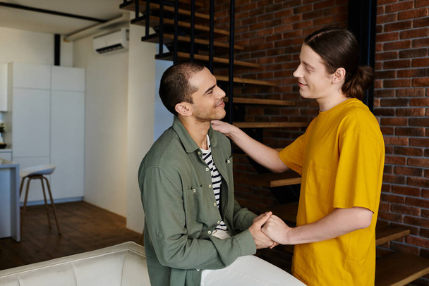 Una giovane coppia gay condivide un momento tenero nel loro appartamento moderno, irradiando amore e connessione. - Foto, immagini