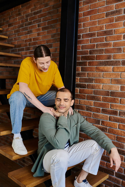 Egy fiatal meleg pár pihen egy modern lakásban, alkalmi öltözéket és intim kapcsolati pillanatot mutatva be.. - Fotó, kép
