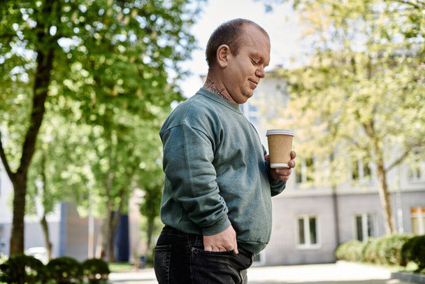 Mężczyzna z inkluzywnością, trzymający filiżankę kawy, spaceruje ulicą miasta. - Zdjęcie, obraz