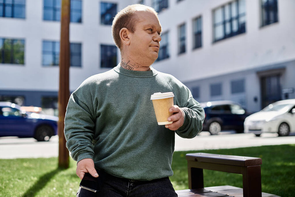 Egy inkluzivitású férfi kávéscsészével a kezében sétál, élvezve a körülötte lévő városi tájat.. - Fotó, kép