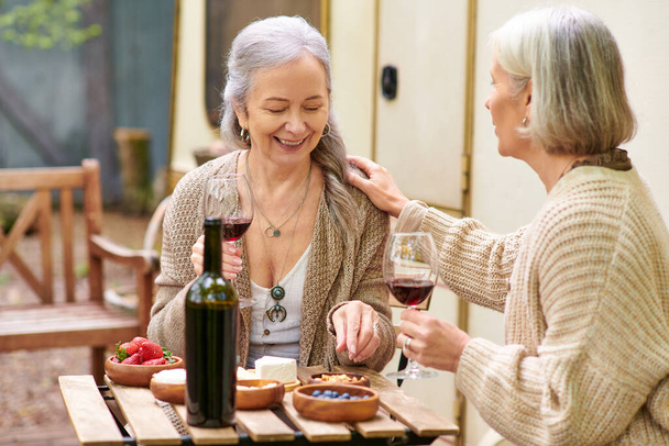 Dvě ženy si vychutnávají víno a smích při kempování v lese. - Fotografie, Obrázek