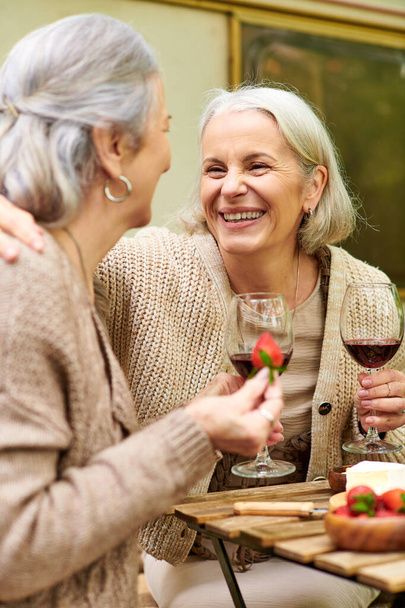 Лесбийская пара наслаждается расслабляющим вечером кемпинг, смеясь и делясь вином. - Фото, изображение
