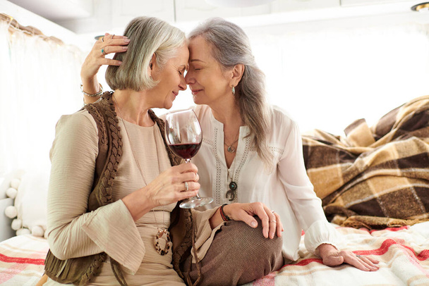 Una coppia lesbica condivide un bicchiere di vino mentre si rilassa nel loro camper. - Foto, immagini
