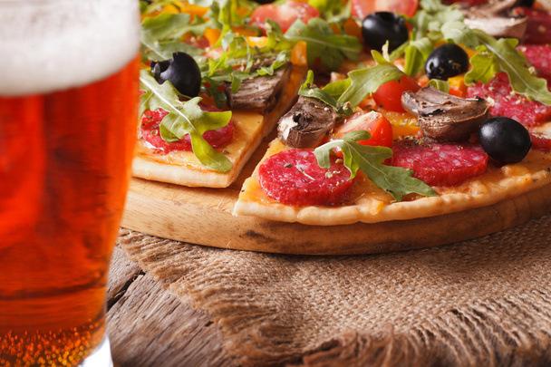 Pizza in Scheiben mit Rucola in Nahaufnahme und Bier, horizontal - Foto, Bild