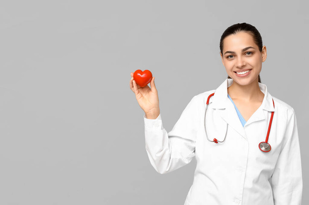 Portrét ženského lékaře se srdcem na šedém pozadí - Fotografie, Obrázek