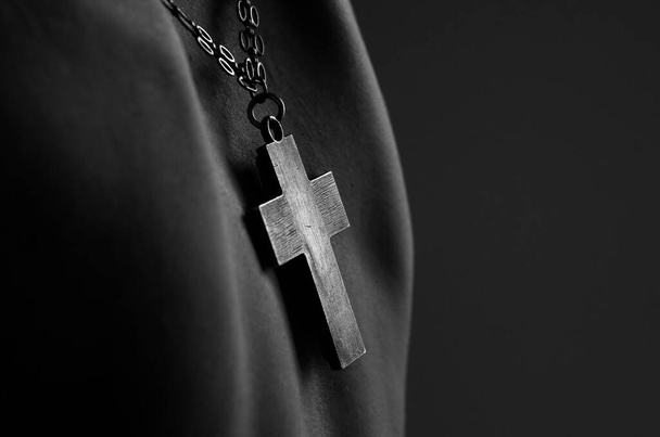 Krzyż wisi na ciele człowieka, symbolizując wiarę i oddanie, dodając potężny, duchowy element do obrazu. - Zdjęcie, obraz