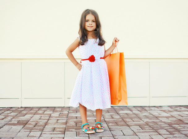 Portrait of beautiful little girl in white dress with shopping b - Fotografie, Obrázek