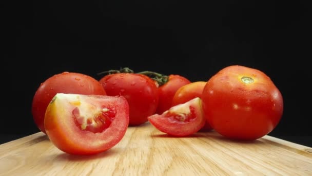 Macrographie, tranches de tomate reposent élégamment sur une planche à découper rustique sur un fond noir dramatique. Chaque gros plan capture la texture juteuse et les couleurs riches des tomates. Comestible. - Séquence, vidéo