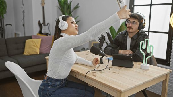Kobieta i mężczyzna robią sobie selfie w studiu radiowym ze sprzętem do podcastów. - Zdjęcie, obraz