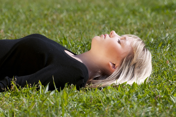 Young woman lying on a meadow - Фото, изображение