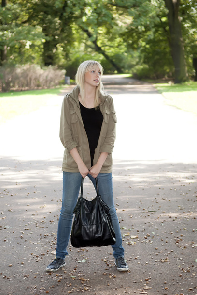 jonge vrouw staat in het park - Foto, afbeelding