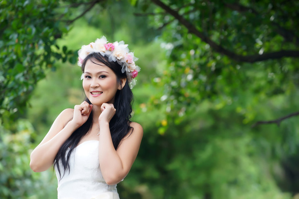 Beautiful Asian lady white bride dress, posing in the forest - Фото, изображение