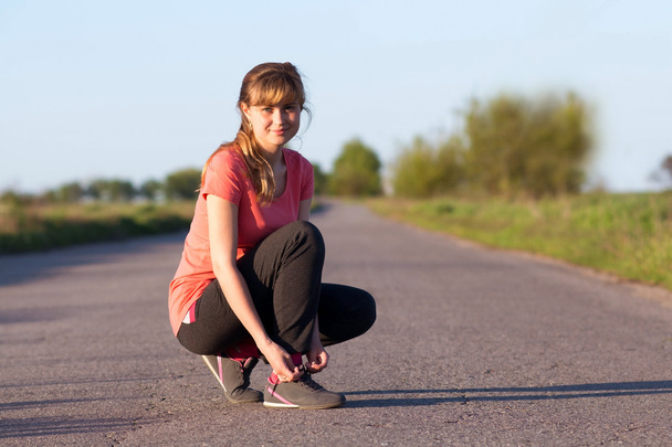 Girl tying shoelaces doing jogging - Photo, Image