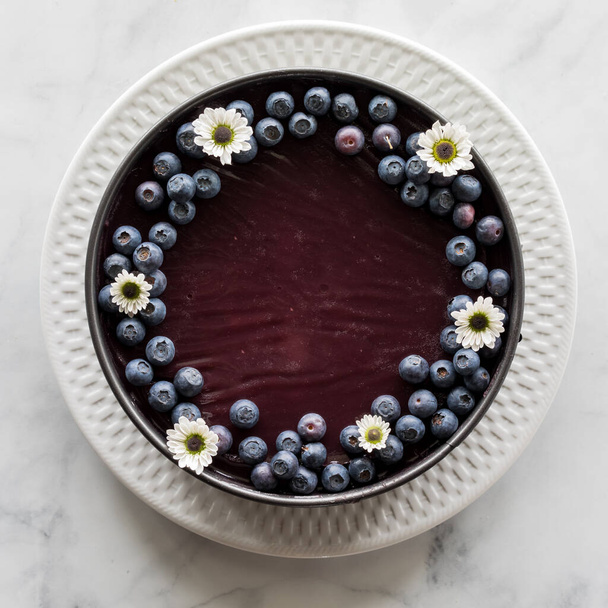 Pohled shora dolů na domácí borůvkový koláč s borůvkami a květinovými květy.  - Fotografie, Obrázek