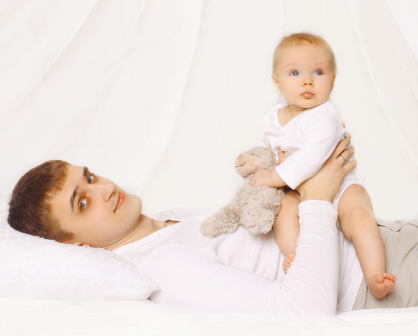 Apja és a baba otthon az ágyon együtt, gyermek játszik - Fotó, kép