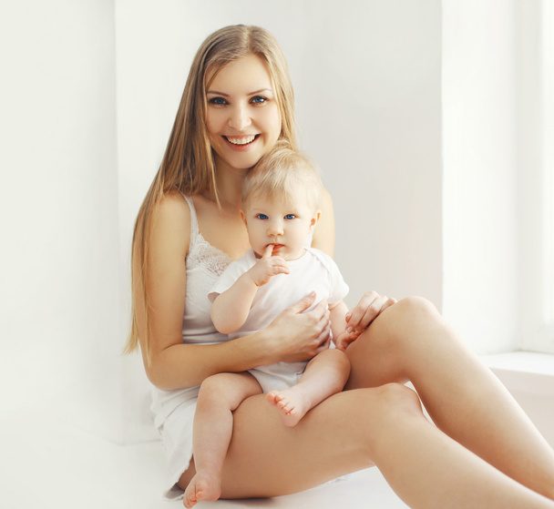 Happy young mother and baby at home in white room - Foto, Imagem