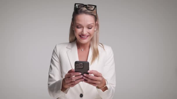 gagnant femme d'affaires avec des lunettes sur le front célébrant avec les mains en l'air tout en regardant le téléphone portable - Séquence, vidéo