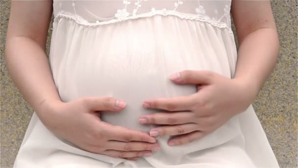Young pregnant woman petting belly feeling the baby, close up - Footage, Video