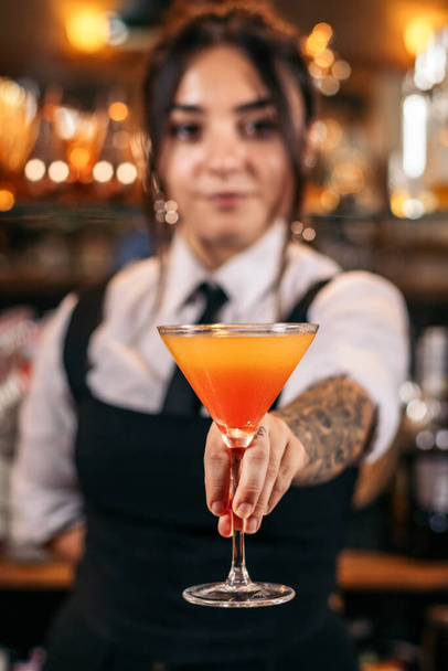 Fiatal nő tetoválásokkal, italokat kínál egy koktélbár bárjában. - Fotó, kép
