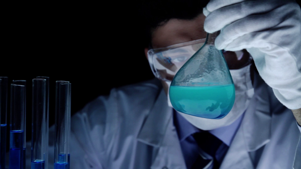 Chemiker mischt Flüssigkeitsmischkolben-Beobachtungsexperiment - Filmmaterial, Video