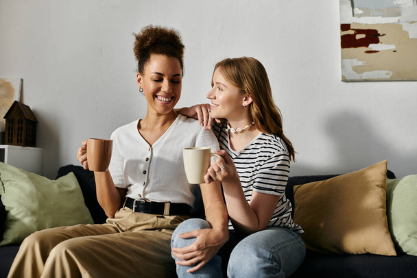 Two women, a lesbian couple, relax and enjoy each others company in a cozy home setting. - Photo, Image
