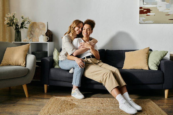 Una coppia lesbica si abbraccia su un divano in un soggiorno, mostrando il loro amore e connessione. - Foto, immagini