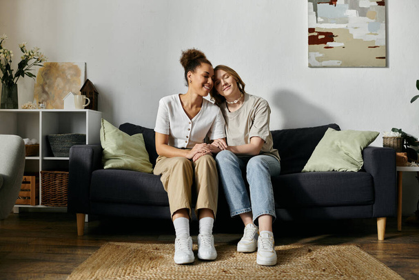 Two women, a lesbian couple, relax on a couch in a home setting. - 写真・画像