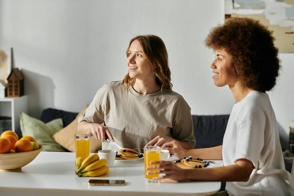 A diverse lesbian couple enjoys a casual breakfast together at home. - Photo, Image