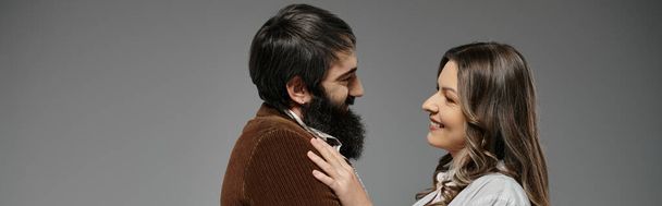 Una pareja con un atuendo sofisticado se miran amorosamente, creando un retrato íntimo y romántico.. - Foto, imagen