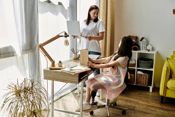 Una madre y una hija están pasando tiempo de calidad en casa, con la hija sentada en un escritorio. - Foto, imagen