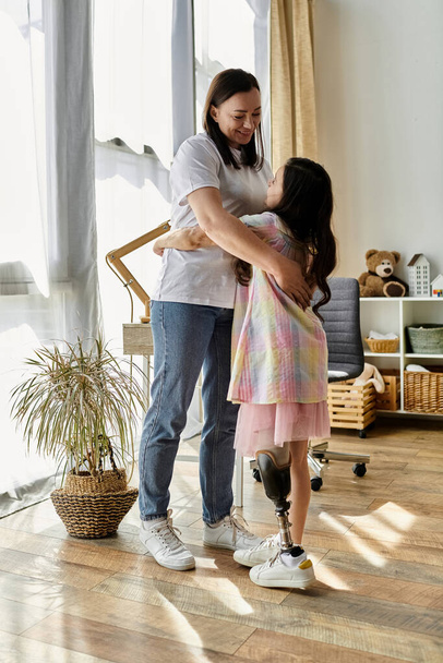 Una madre bruna e sua figlia con una gamba protesica abbracciano a casa, mostrando il loro legame amorevole e la gioia della vita di tutti i giorni. - Foto, immagini