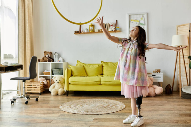 Młoda dziewczyna z protezą nogi bawi się w domu, pokazując radość i odporność dziecka żyjącego z niepełnosprawnością. - Zdjęcie, obraz