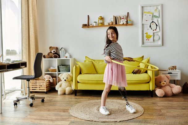 Ein junges Mädchen mit Beinprothese dreht freudig einen Hula-Hoop-Reifen in ihrem Wohnzimmer, umgeben von Spielzeug - Foto, Bild