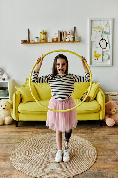 Uma jovem com uma perna protética sorri enquanto brinca com um arco de hula em sua sala de estar. - Foto, Imagem