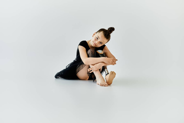 Una joven con una pierna protésica se sienta en una pose gimnástica. - Foto, imagen
