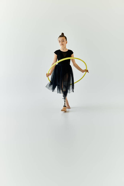 Mladá dívka s protézou nohy provádí hula obruč rutina v bílém studiu. - Fotografie, Obrázek