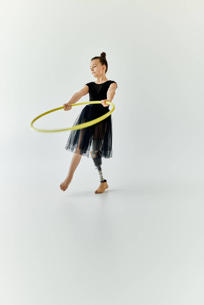 Uma jovem com uma perna protética pratica ginástica, girando um aro. - Foto, Imagem