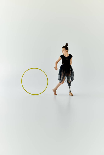 Une jeune fille avec une prothèse de jambe pratique la gymnastique avec un cerceau. - Photo, image