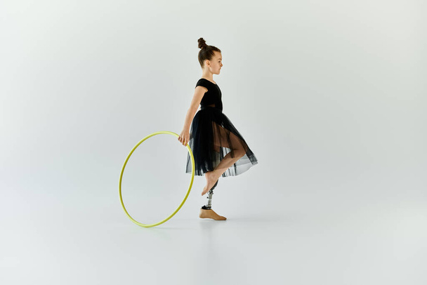A young girl with a prosthetic leg gracefully performs a gymnastics routine with a hoop. - Foto, imagen