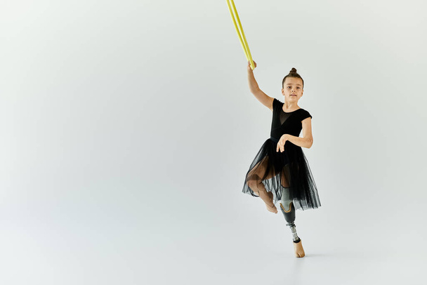 Uma jovem com uma perna protética executa uma pose de ginástica graciosa em um tutu de balé. - Foto, Imagem