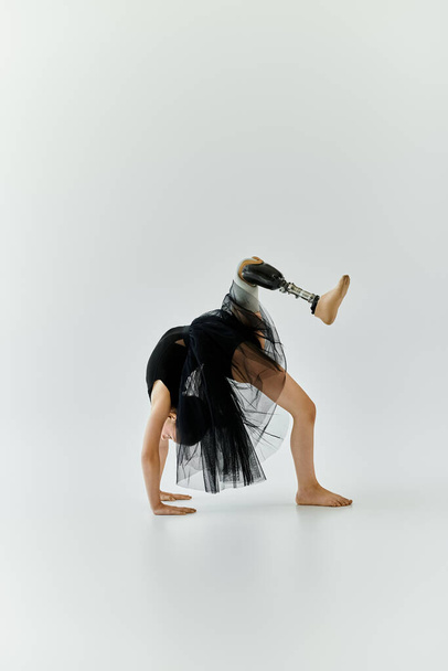 Une jeune fille avec une jambe prothétique effectue une pose de gymnastique, démontrant une force et une agilité incroyables. - Photo, image