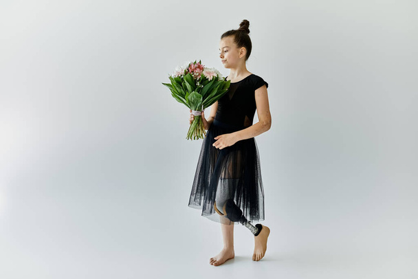 Ein junges Mädchen mit Beinprothese hält einen Blumenstrauß in einem Atelier. - Foto, Bild