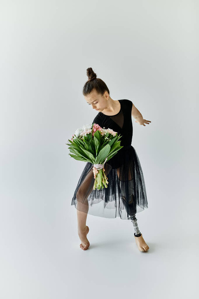 Молодая гимнастка с протезной ногой изящно позирует, держа букет цветов. - Фото, изображение