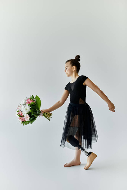Ένα νεαρό κορίτσι με προσθετικό πόδι χορεύει χαριτωμένα με ένα μπουκέτο λουλούδια.. - Φωτογραφία, εικόνα