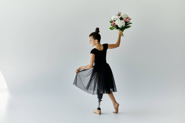 Eine junge Ballerina mit Beinprothese hält anmutig einen Blumenstrauß in der Hand. - Foto, Bild