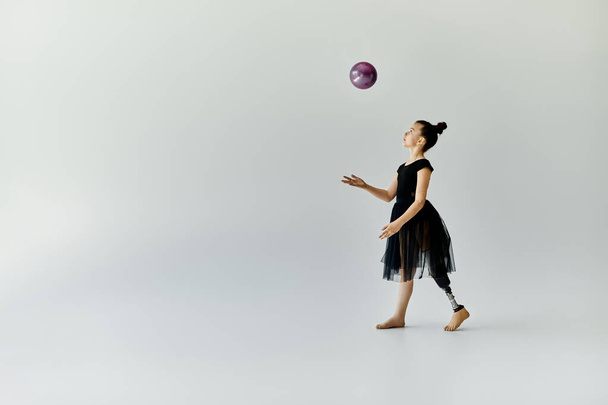 Una joven con una pierna protésica lanza con gracia una pelota durante una rutina de gimnasia. - Foto, imagen